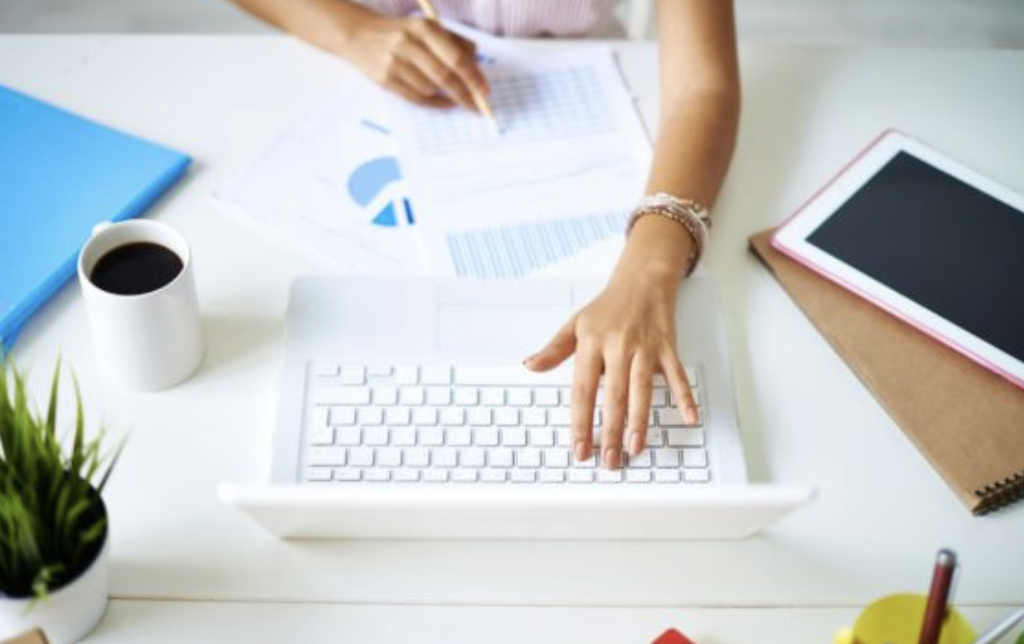 Escritorio con portátil, informes y café mientras se revisa la contabilidad